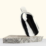 Stainless steel indoor potting scoop on a stone surface with a white background