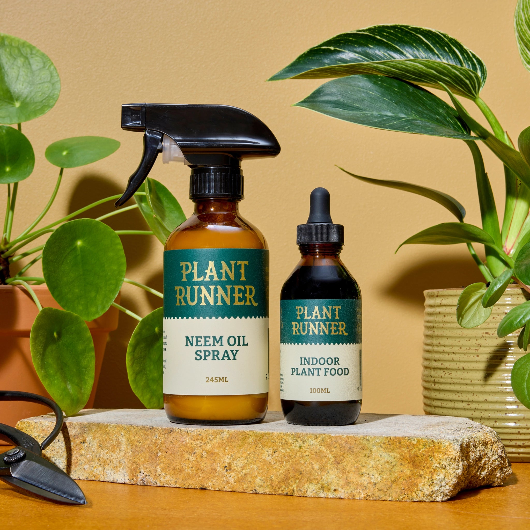 Two plant care products from Plant Runner on a stone surface with plants in the background.
